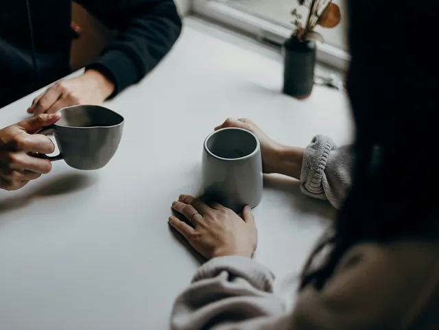 Besøgsvenner drikker kaffe ved bordet